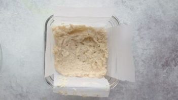 bread batter in a glass baking dish lined with strips of white parchment paper