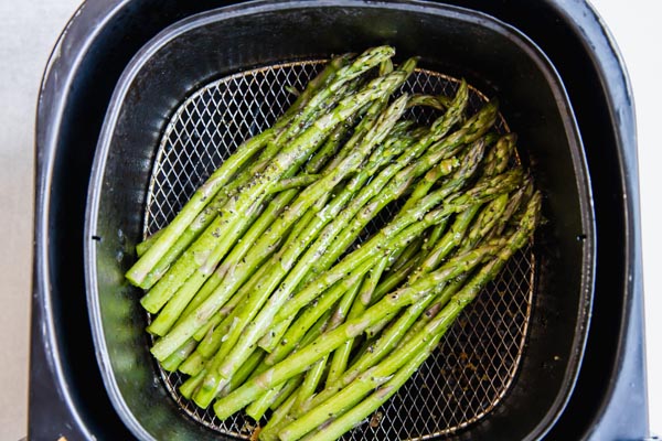 asparagus spears in an air fryer basket