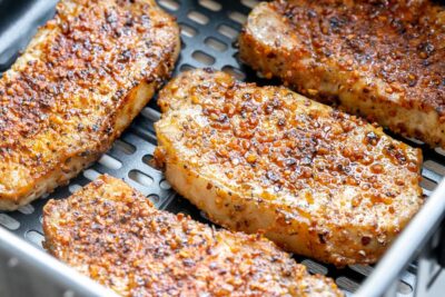 Juicy pork chops in an air fryer basket.