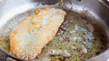 fried rockfish fillet frying in a skillet with hot oil