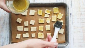 brushing olive oil herb mixture on top of crackers