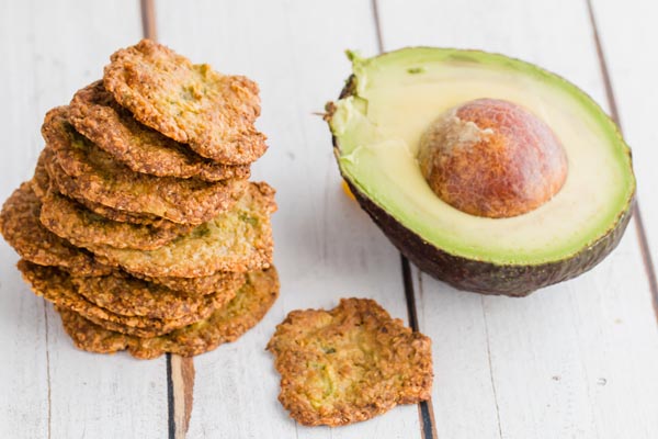 a bunch of avocado chips next to a half a avocado