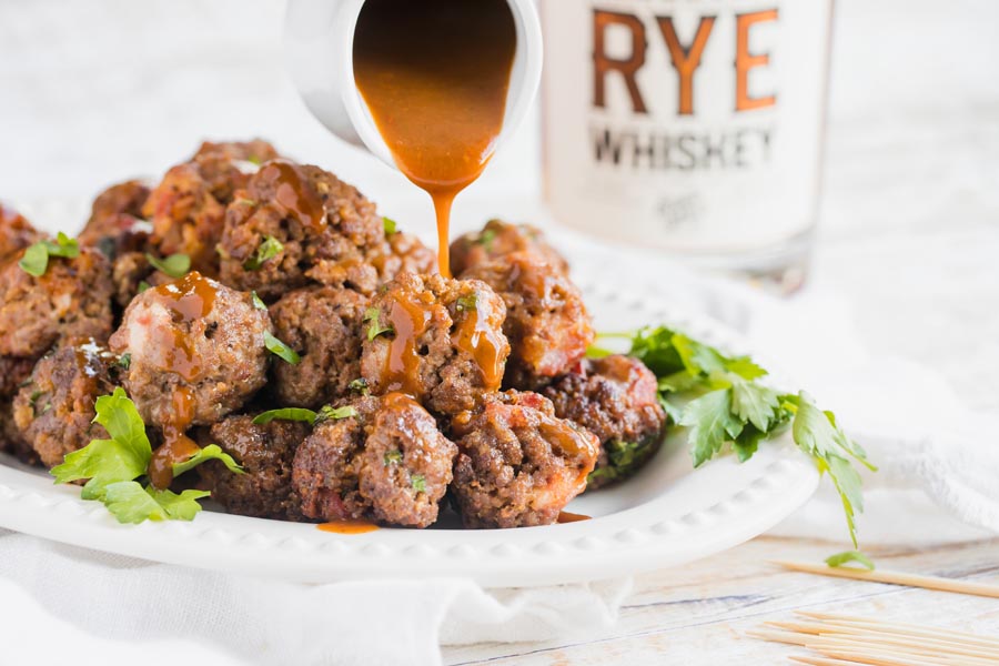 pouring bbq sauce on top of air fryer meatballs