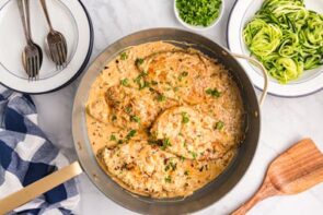 A skillet filled with creamy boursin chicken topped with parsley.