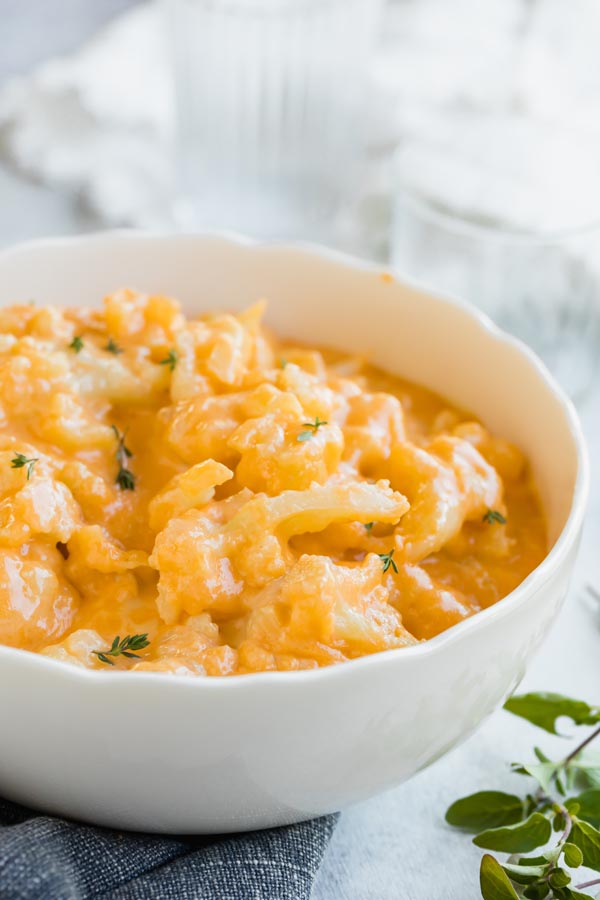 a bowl of cheesy keto cauliflower mac and cheese topped with thyme