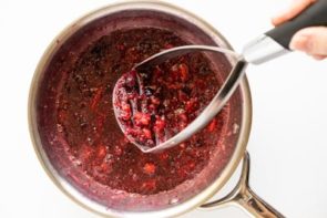 mashing berries with a potato masher