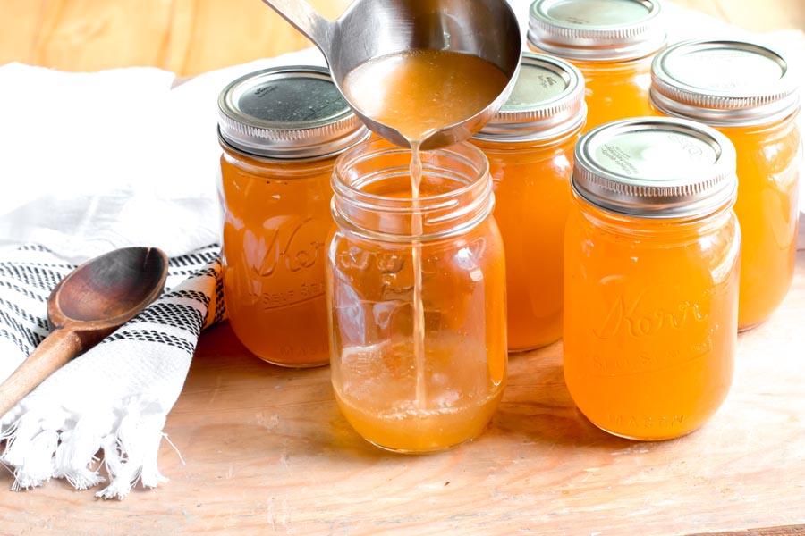 pouring chicken bone broth in a mason jar