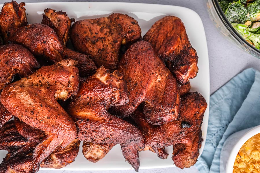 a bunch of wings on a white plater with a blue napkin