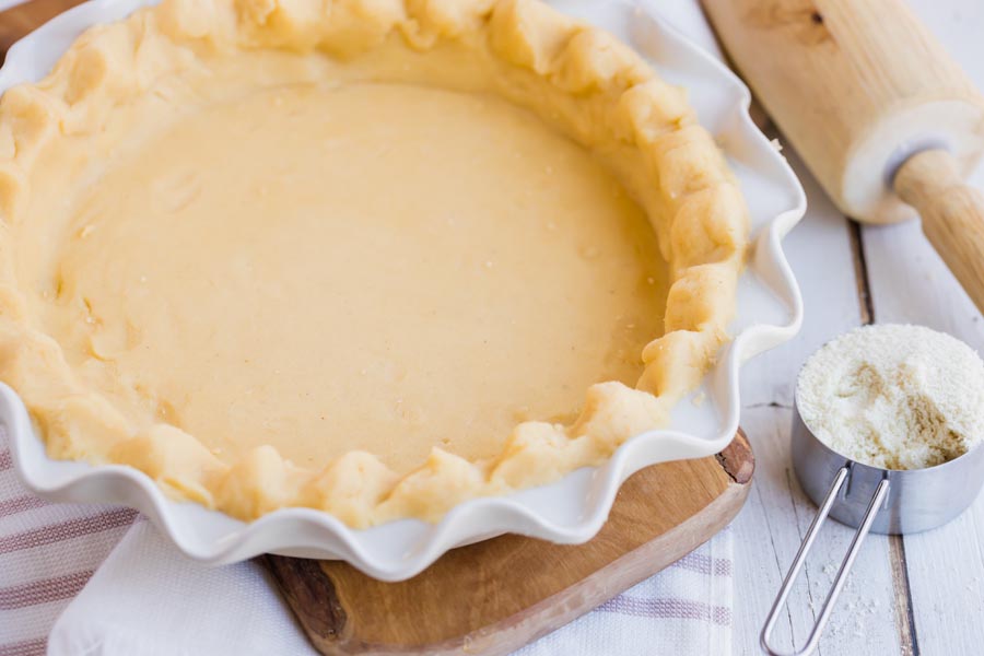 pie crust pressed into a pie plate with a rolling pie and almond flour cup