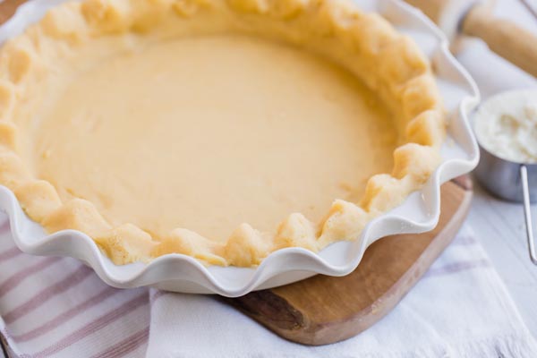 unbaked pie crust in a plate with rolling pie next to it