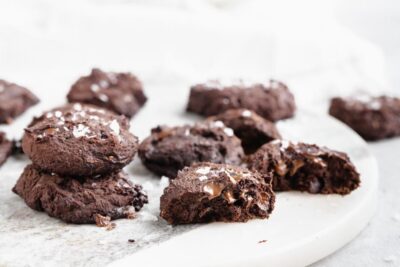 a group of cookies on a counter top with a cookie cut in half showing the melted chocolate inside