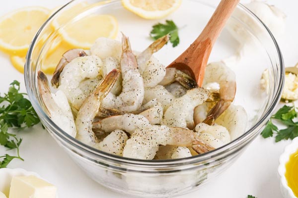 raw shrimp in a bowl dusted with fresh cracked black pepper