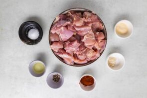 A big bowl of chicken bites surrounding by little bowls filled with seasoning.