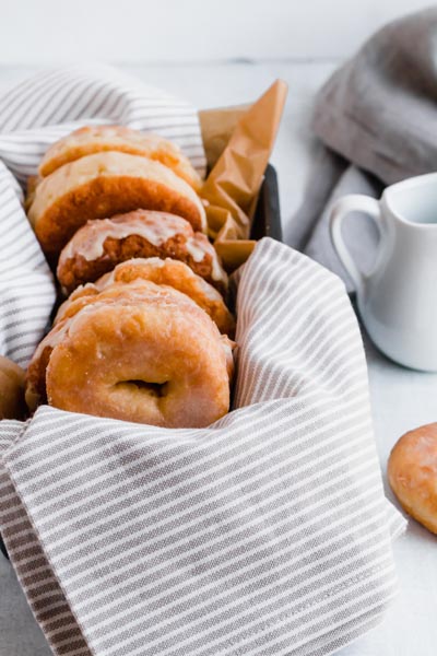 donuts tucked into a baking dish over a gray striped towl