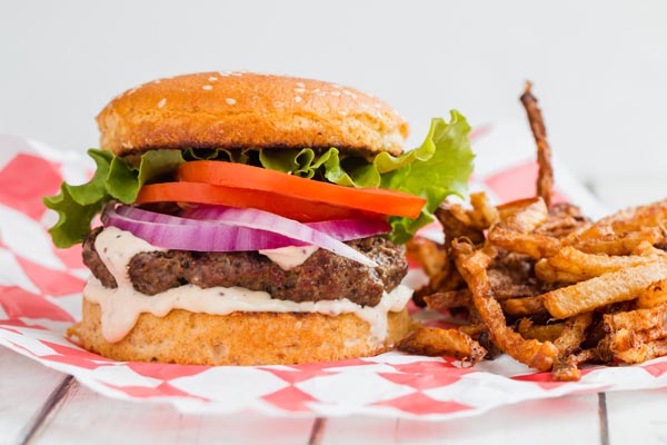 grilled keto burger with sauce and all the fixings with a low carb bun and jicama fries