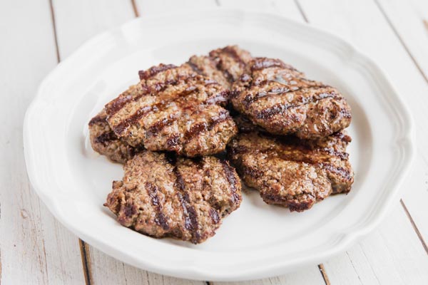 a bunch of grilled hamburger patties on a plate