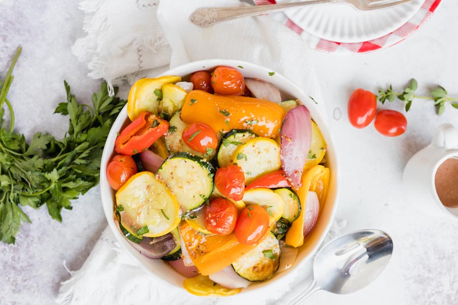 a large bowl of vegetables next to plates and fresh herbs