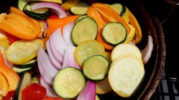 squash, onion and peppers grilling in a grill basket