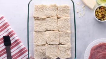 Keto dinner rolls sliced in half with the bottom halves inside a baking dish.