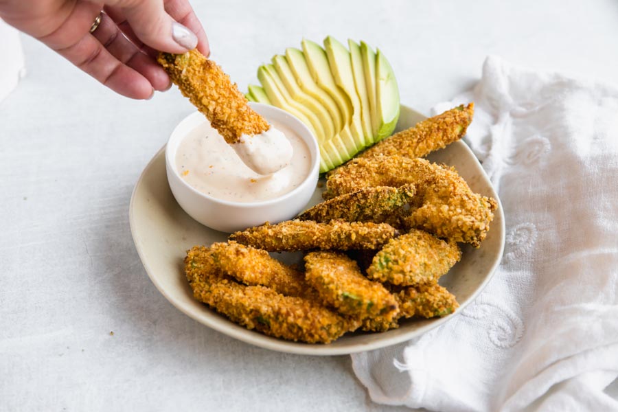 dipping an air fryer avocado fries into ranch dressing