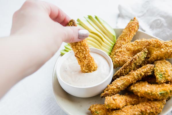 dipping a keto avocado fry into ranch dressing