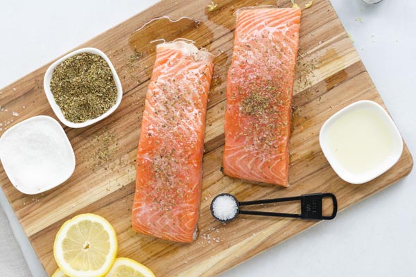 sprinkling black pepper on a salmon fillet