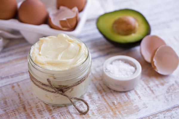 a container of mayonnaise by egg shells salt and lemon rinds