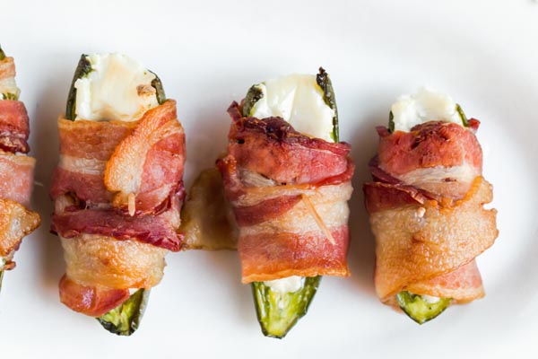 Keto jalapeno poppers in a row with crispy bacon