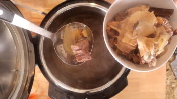 straining out bones and onions with a slotted spoon