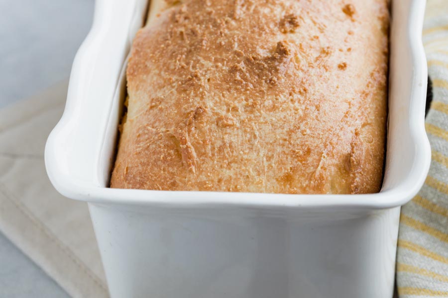 a baked loaf of bread in a white loaf pan