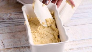 spreading bread dough into a loaf pan using a spatula