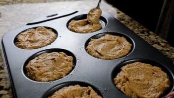 scooping muffin batter into a pan with a spoon