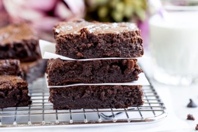 a stack of brownies on a tray with milk in the background