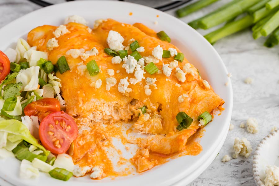 enchilada dinner with side salad and casserole dish behind