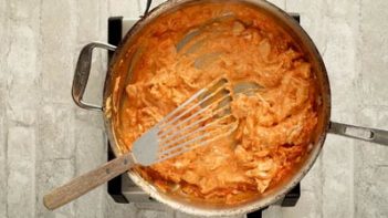 buffalo chicken simmering in a skillet