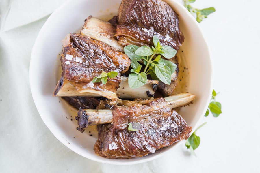 overhead view of a bowl of short ribs in braising liquid