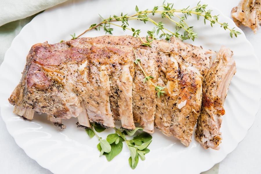 pork ribs cooked on a white platter with thyme near