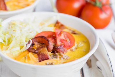 bacon strips, lettuce and tomatoes on an orange creamy soup