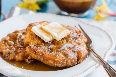 a fork sits next to chicken and waffles on a plate