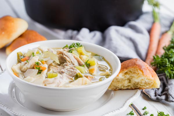 a hearty bowl of soup with a bread roll on the side