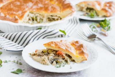 a savory slice of pie on a dinner plate next to forks with another slice on a plate in the background