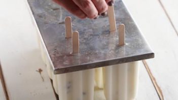 sliding a popsicle stick into a popsicle mold