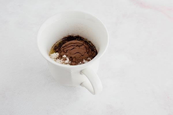 chocolate mug cake ingredients piled into a white coffee mug