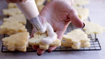 Piping frosting onto a small cake shaped like a tree.