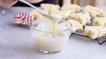 A spoon with thin melted white chocolate melting down.