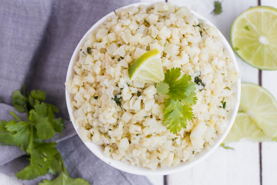 looking down on a bowl of cauli rice garnished with lime wedges