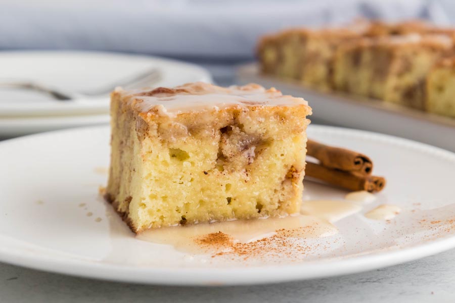 A slice of coffee cake topped with a vanilla glaze and dusted with cinnamon.