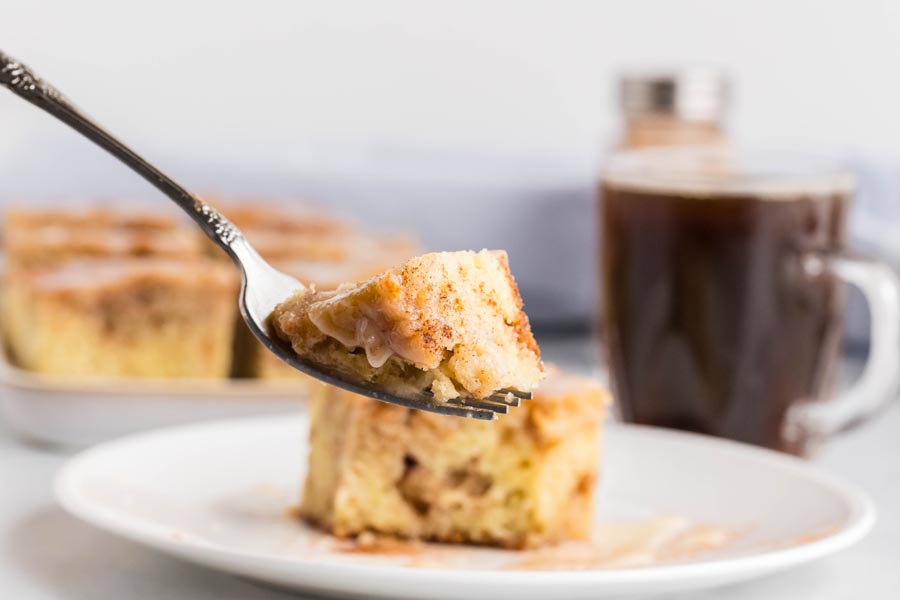 A fork holding a bite of cinnamon coffee cake.