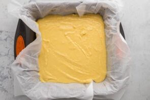 Yellow cake batter sitting inside a parchment lined baking dish.