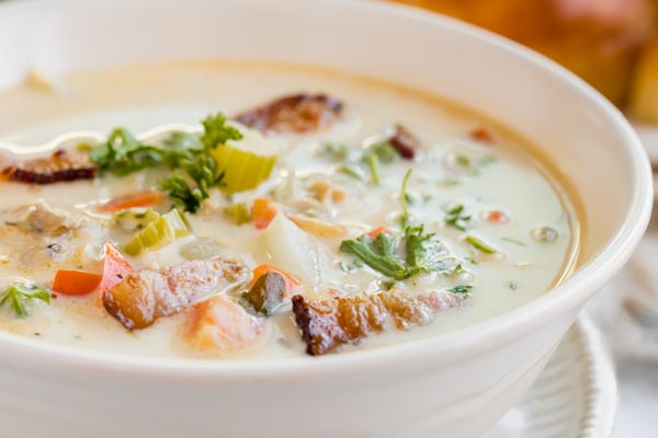 crispy bacon on top of a chunky clam chowder in a bowl